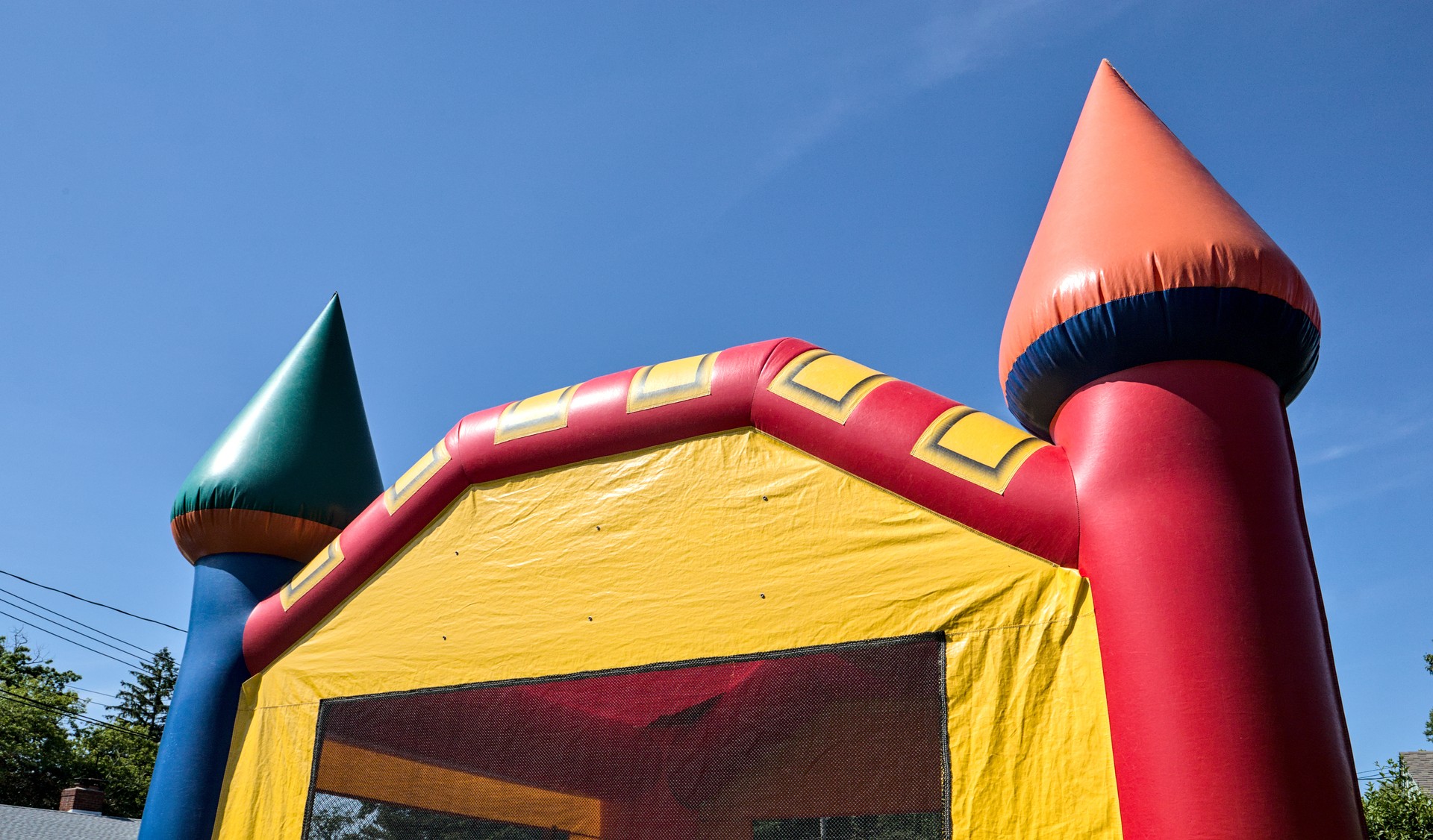 bouncy castle children's toy (bounce house for kids) close up detail silhouette against sky (colorful toy playground party blow up inflatable birthday block party rental rented rent) bouncing jumping