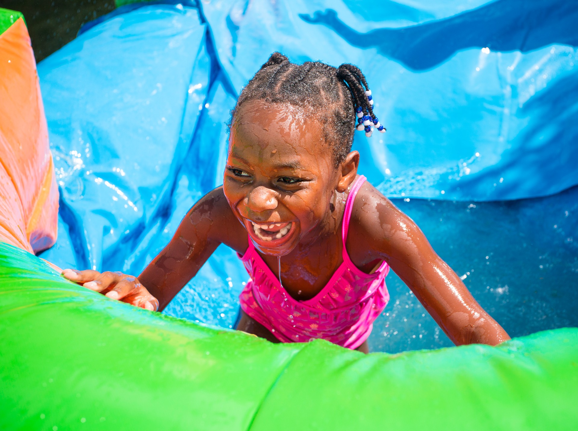 Smiling little girl playing on an inflatable water slide